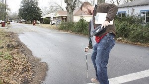 LEAKS: Zack Malley, field supervisor in the city water and gas department, checks for leaks along a gas line after first checking the sewer manhole at the corner of Rowland and Mill streets for the presence of gas.  Photo by Will Sullivan 