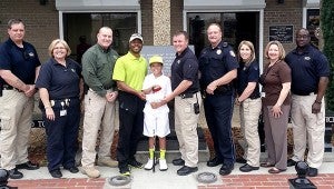 Officers of the Picayune Police Department gathered to present Cameron Guidry with a check to help defray costs of his trip to an international competition. Shown from left are: James Bolton, Theresa Milar, Picayune Police Chief Bryan Dawsey, Cory Guidry with his son Cameron Guidry, Lane Pittman, Gary Wilton, Christa Groom, Ginger Bennett and Lamar Thompson. Jodi Marze | Picayune Item 