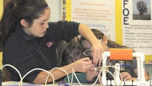 TEAMWORK: Students in Alicia Verwij’s fifth grade class at Roseland Park Elementary work together too tighten the plastic ties that attach the motors to the group’s Remotely Operated Vehicle.  Photo by Alexandra Hedrick