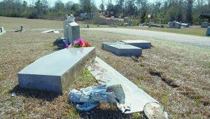 SETTING IT RIGHT: Employees with Magnolia Monument Company reset grave stones knocked over by an unknown suspect Thursday night. About seven grave stones were knocked over by the vehicle at the First Baptist Church of Carriere. 