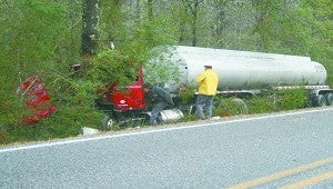 Emergency personnel work to drag this 18-wheeler from the woods Tuesday afternoon.
