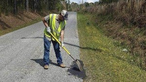 FILLING IN THE HOLES: A member of the Pearl River County Road Department works on fixing a pothole Tuesday afternoon. Both the county road department and Poplarville Public Works have seen an increase in potholes this year.  Photo submitted.  