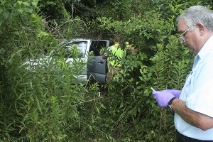 MEDICAL RESPONSE: Emergency personnel worked an accident at mile marker 7 on Interstate 59 Tuesday morning. The driver was pronounced dead at the scene.  At right Pearl River County Deputy Coroner Albert Lee calls the state medical examiner’s office to schedule an autopsy. Photo by Jeremy Pittari