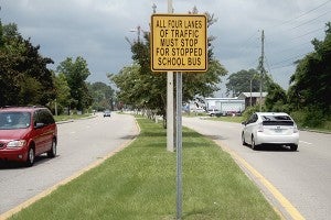 ALL MUST STOP: Signs posted along Main Street in Picayune remind drivers that all four lanes of traffic are required to stop when a school bus does. Photo by Jeremy Pittari